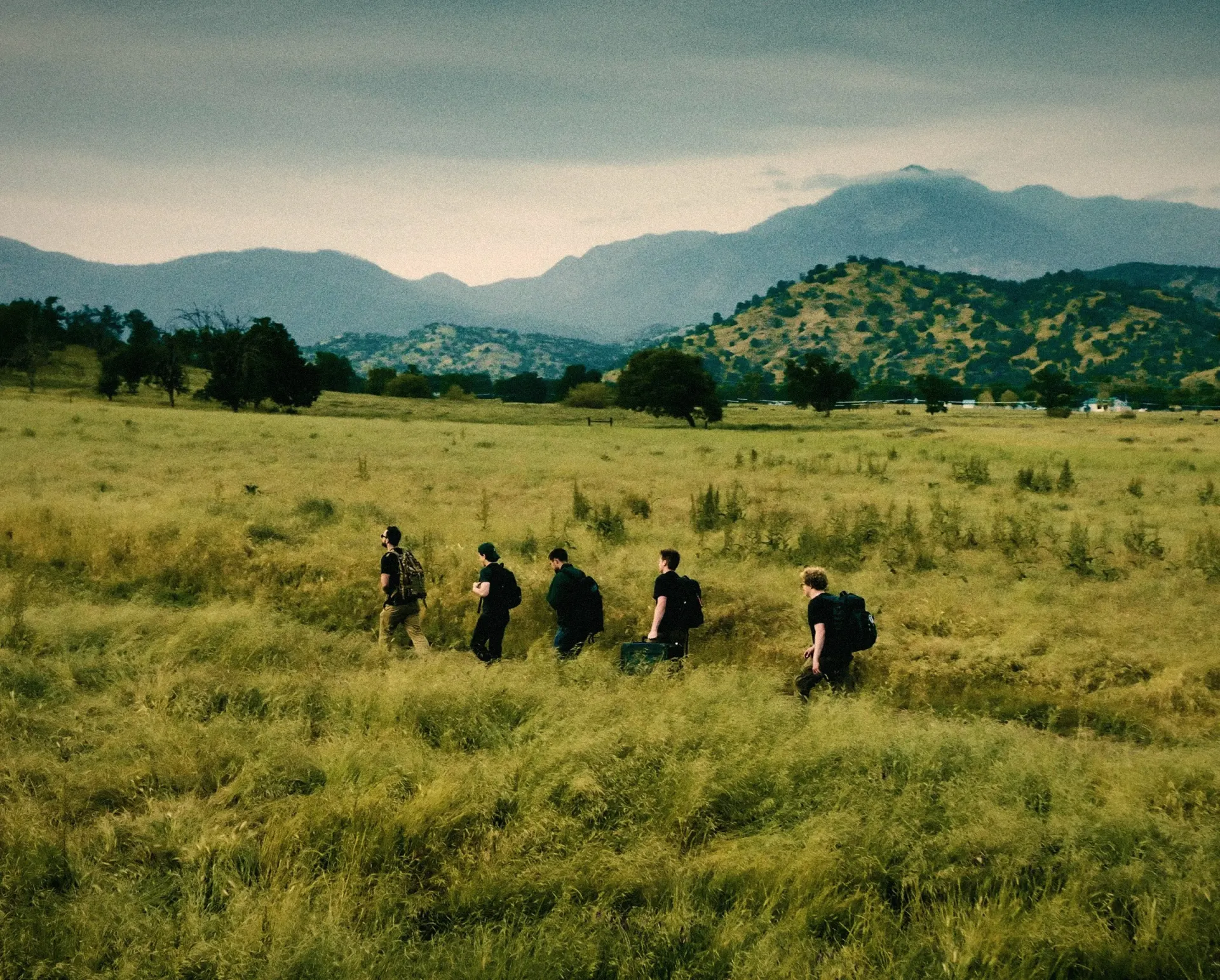 The Rainmaker field team walking through a valley meadow toward the mountains